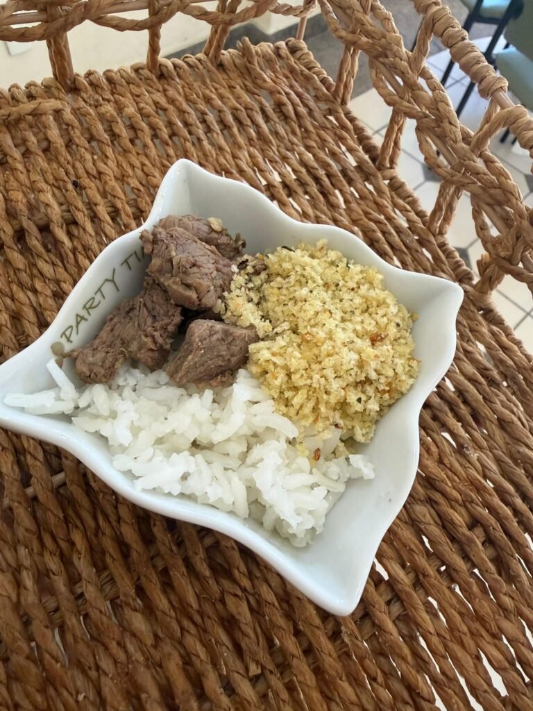 Prato com carne, arroz e farofa servido em petisqueira